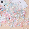 A scattered collection of mixed resin rhinestone pearls with an AB finish in various shades of pink, blue, and white.
