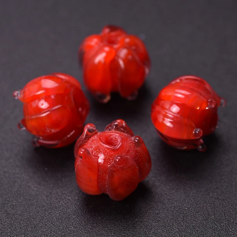 Several small, glossy red glass charms shaped like lily of the valley buds for jewelry making
