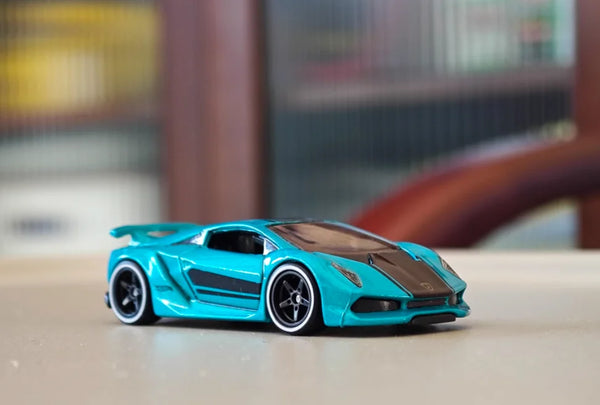 A bright turquoise 1/64 scale sports car model with black accents sitting on a light surface.