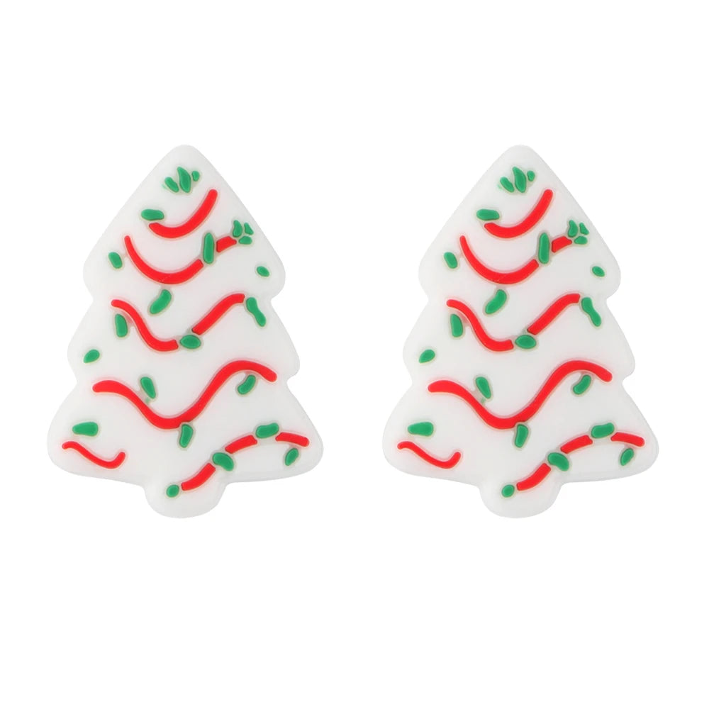 Two white silicone beads shaped like Christmas trees decorated with red and green lines for jewelry making