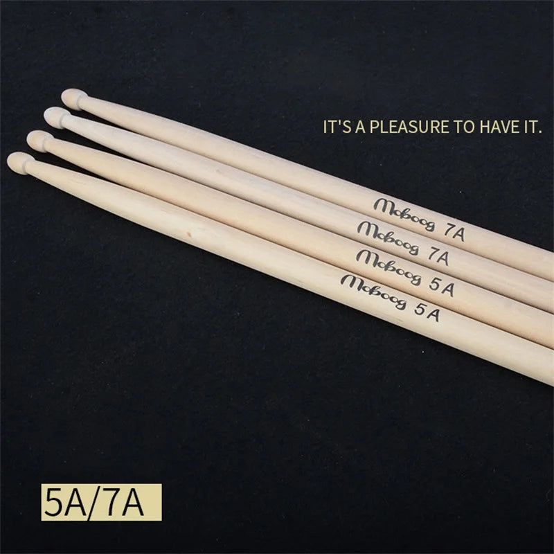 A pair of light wood drumsticks labeled Moboog 7A and Moboog 5A are displayed on a dark surface.