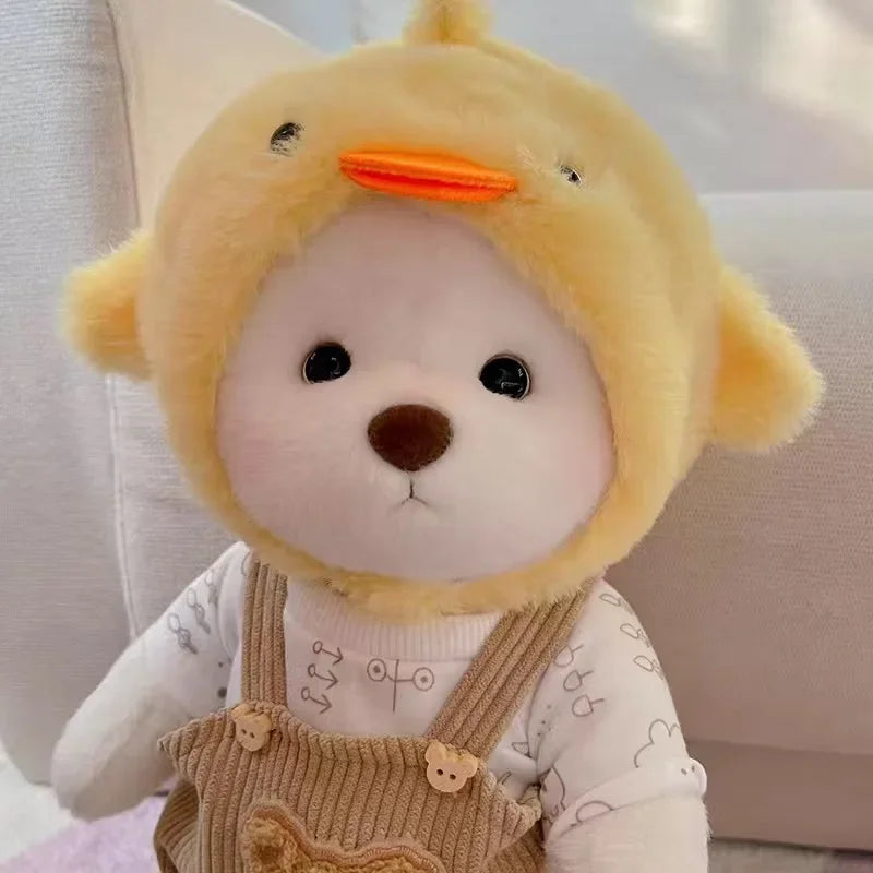 A yellow teddy bear plush wearing a light-colored shirt and overalls.