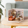 A miniature house kit display featuring a cozy living room scene with furniture and decorative elements.