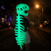 A glowing green dinosaur skeleton mask is displayed outdoors in a dark, foggy setting.