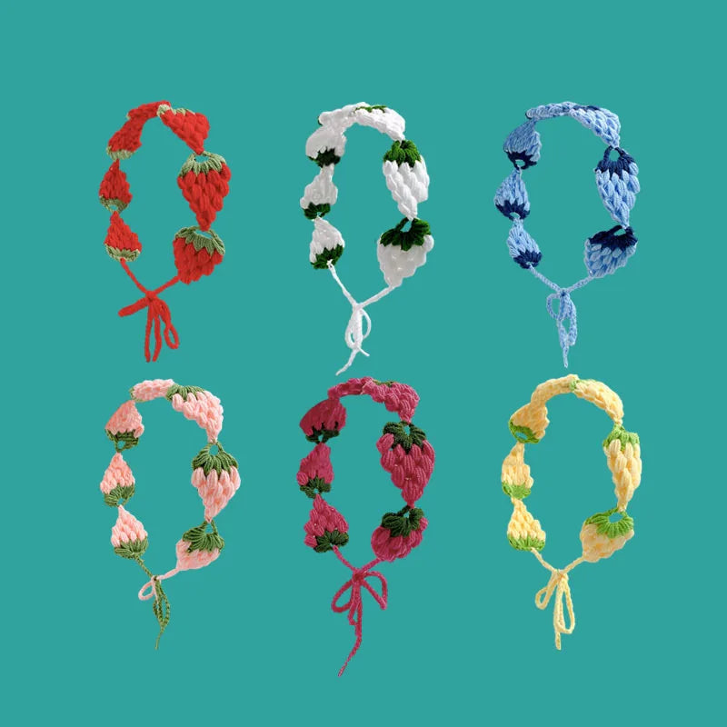 A collection of handmade strawberry crochet headbands in various shades of red, green, and blue.