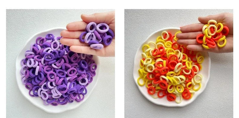 A hand holds a white dish filled with colorful nylon hair ties in purple and orange shades.