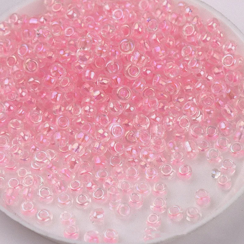 A close-up view of pink glass rice beads scattered in a white dish for crafting and jewelry making