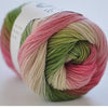 A ball of hand-dyed merino wool yarn in shades of pink, green, and cream, coiled for knitting or crochet.