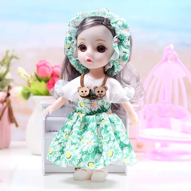 A 17cm articulated princess doll with a white dress and green floral outfit, featuring a ruffled hood and bear-themed necklac