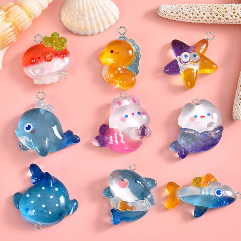 A collection of colorful resin charms shaped like sea creatures including a strawberry, duck, dolphin, and fish.