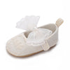 A pair of light beige lace-trimmed baby girl moccasin shoes with a decorative bow.