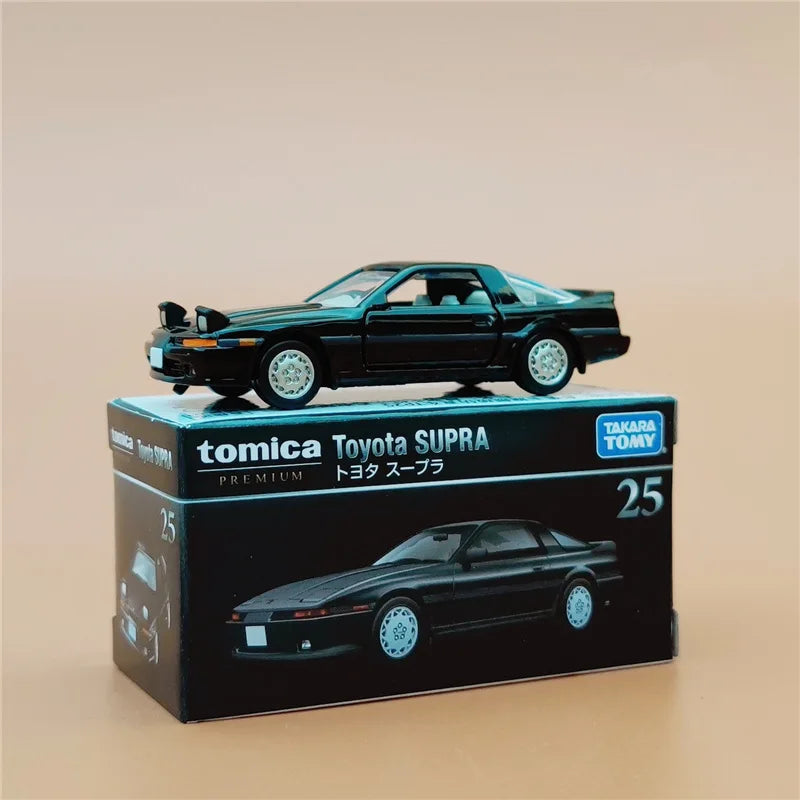 A black Toyota Supra die-cast model car displayed in its packaging box.