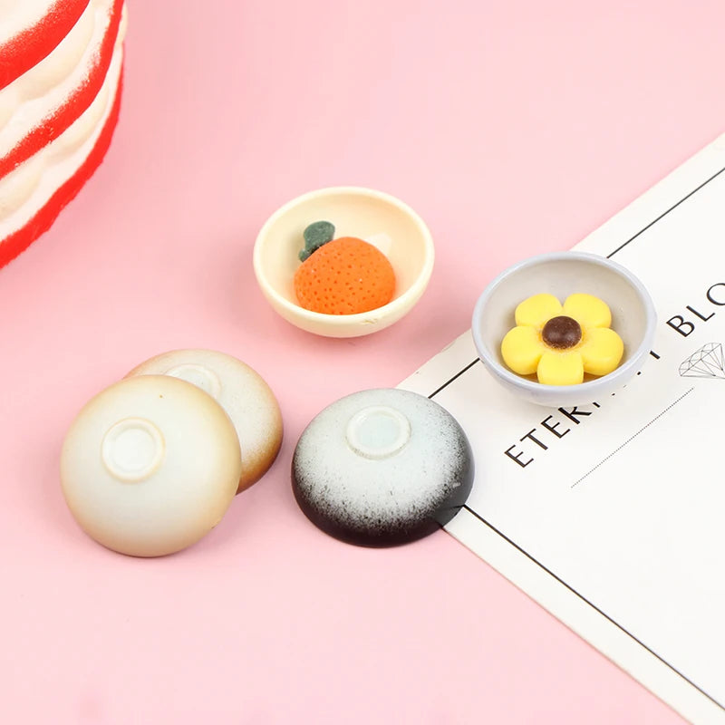 A set of ten miniature rice bowls, some filled with orange grains and others empty, displayed on a pink background.