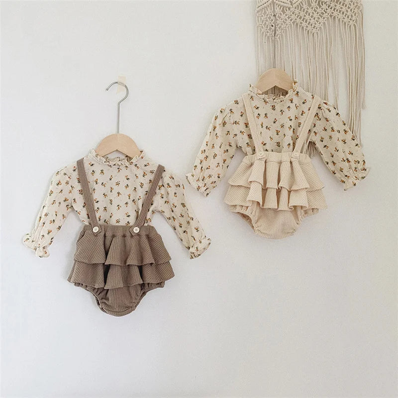 A vintage floral baby girl outfit set featuring a long-sleeved blouse and matching ruffled romper.