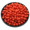 A pile of bright orange acrylic round beads for jewelry making in various sizes.