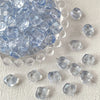 A pile of irregular square geometric glass beads for jewelry making on a light surface.