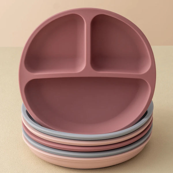 A stack of pink silicone baby sucker dining plates on a light background.