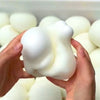 A hand is squeezing a white squishy bread stress ball among many similar toys.