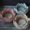 Three silicone flower molds in pink and light blue holding candles or small items.