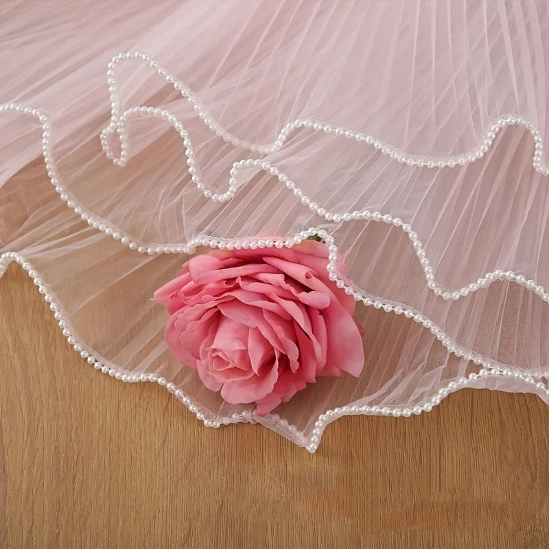 A pink rose is placed on sheer pink mesh fabric with white pearl trim.