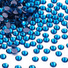 A close-up view of various blue glass crystal hot fix rhinestones scattered on a white background.