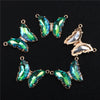 A set of gold-toned crystal butterfly charm beads for jewelry making, featuring iridescent green and blue butterfly shapes.