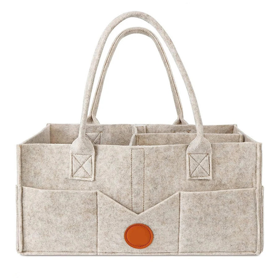 A beige felt diaper storage bag with long handles and a structured design.