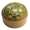 A round, olive green squishy toy shaped like a dumpling with gold glitter speckles and simple black eyes.