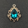 Gold plated water droplet charm featuring a brilliant blue crystal rhinestone set in an ornate flower design.