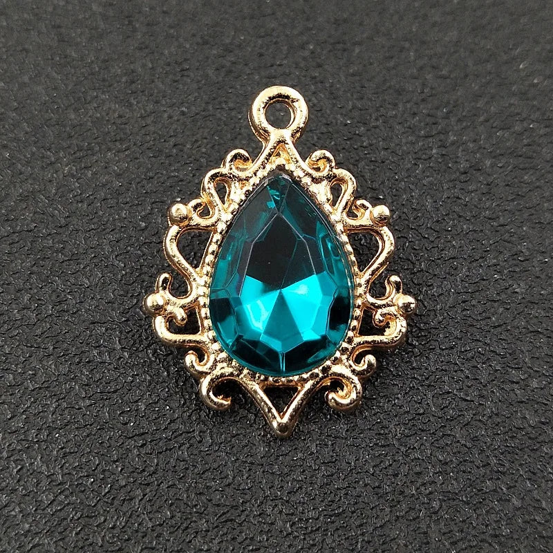 Gold plated water droplet charm featuring a brilliant blue crystal rhinestone set in an ornate flower design.