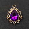 Gold plated water droplet charm featuring a purple crystal rhinestone set in an ornate flower design.