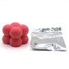 A pile of pink candle dye chips next to a small silver foil packet.
