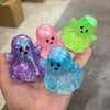 Three translucent stress relief balls in purple, pink, and blue glow in a hand.