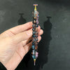 A hand holds a colorful diamond painting pen with a stainless steel tip, displaying iridescent and multi-colored beads.