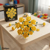 A bouquet of yellow rose-shaped building blocks is displayed on a wooden table.