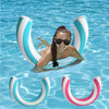 A woman floating in clear blue water surrounded by striped inflatable U-shaped pool floats.