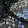Nahaufnahme von irisierenden und glitzernden Harzperlen in Schwarz, Silber und Blautönen.