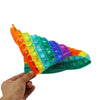 A hand holds a colorful multiplication pop-it fidget toy with numbered silicone bubbles.