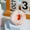 A pink, squishy stress relief ball is displayed on a white block next to a wooden calendar.