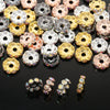 A close-up of various 12mm crystal rhinestone spacer beads in gold, silver, and rose tones.