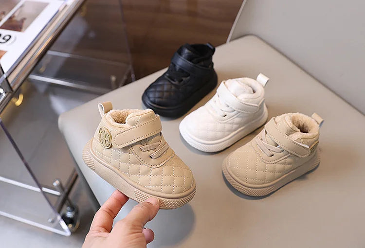 A pair of beige quilted toddler winter snow boots with soft soles and Velcro closures are shown on a light surface.