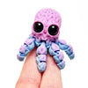 A purple and blue 3D printed articulated octopus figurine resting on a hand.