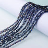 A strand of dark blue and purple faceted glass crystal beads draped across a white surface.