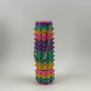 A stack of colorful, hexagonal spike rollers or fidget toys in shades of pink, purple, green, and yellow.