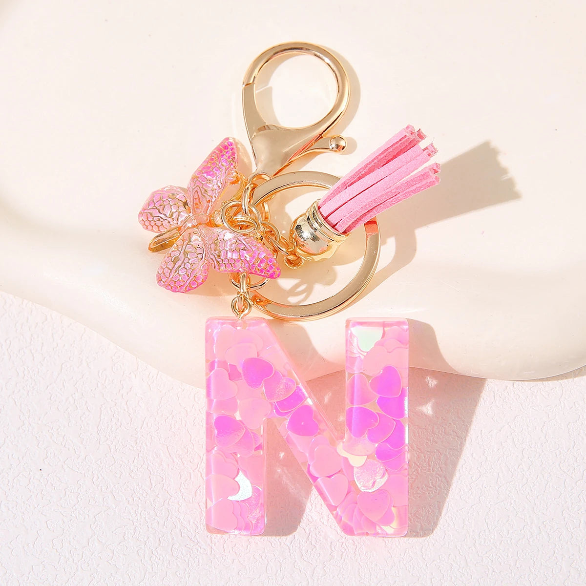 Gold initial heart keychain featuring a pink butterfly charm and a pink acrylic letter N.