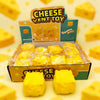 A box of yellow cheese squeeze fidget toys with several yellow squishy toys displayed on the surface.
