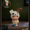 A white bunny collectible figure with pink accents and a red ear, displayed on a wooden surface.