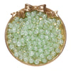 A round gold-rimmed dish filled with small, light green glass crackle beads for jewelry making.