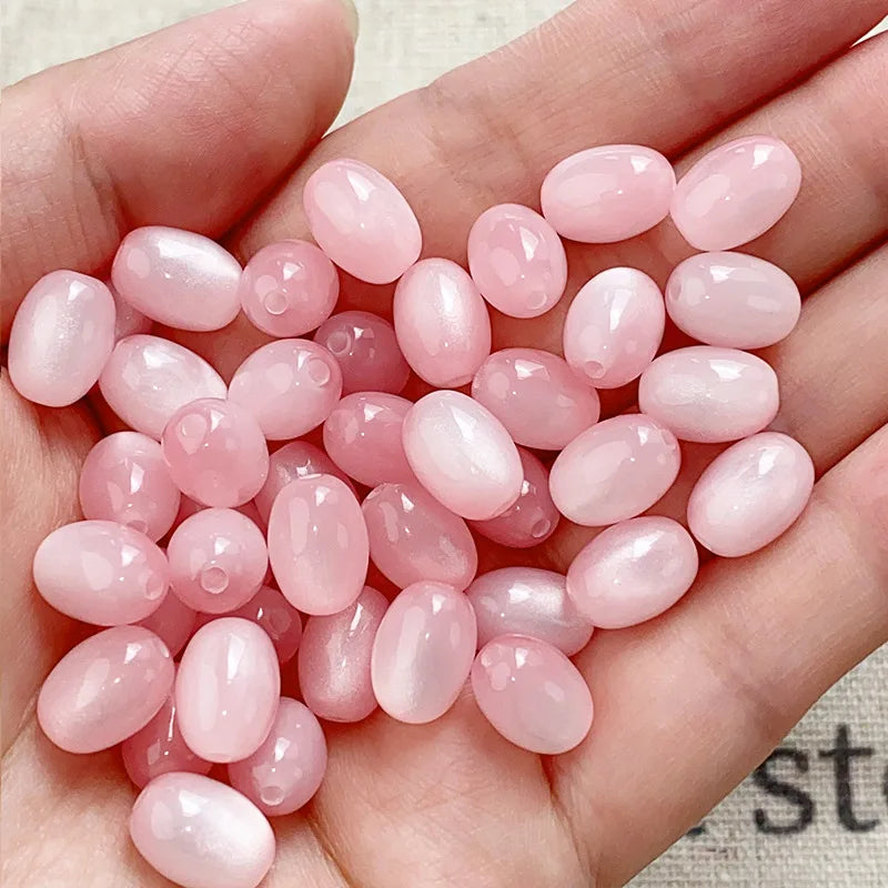 A hand holds a pack of ten pink and rosy translucent resin star-like beads for jewelry making.