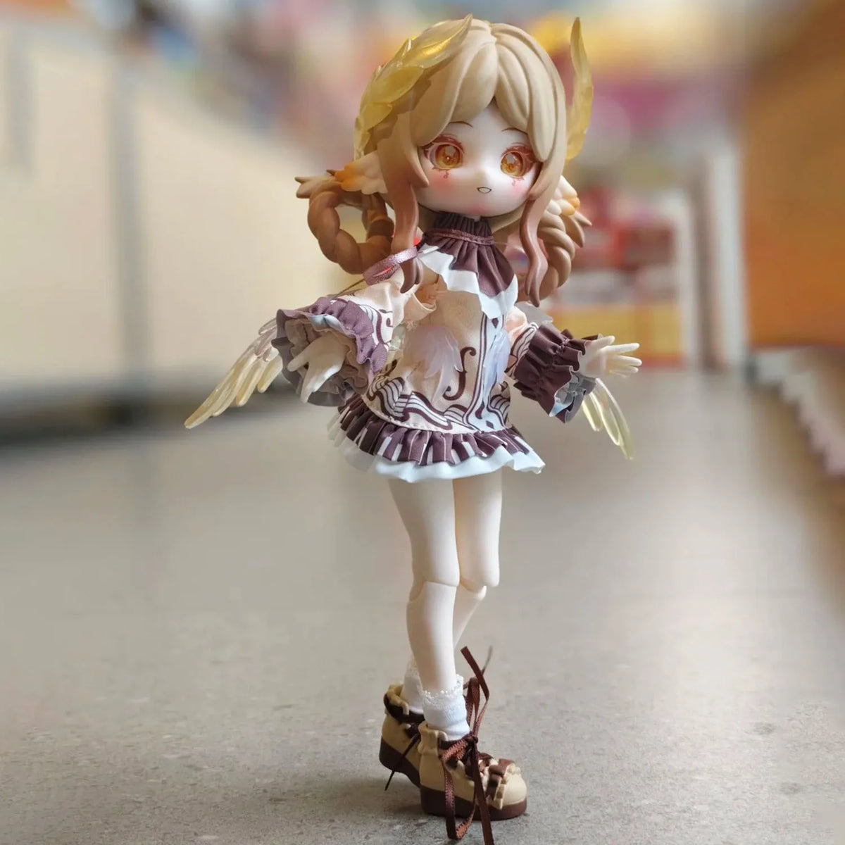 A detailed articulated ball-jointed doll with blonde hair and wings in a white and purple outfit standing on a surface.